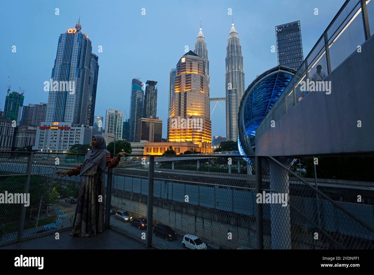Kuala Lumpur, Malesia - 29 luglio 2023: Donna musulmana in posa per una foto di fronte al ponte di Saloma e alle iconiche Petronas Towers, situate nel KLCC. Foto Stock