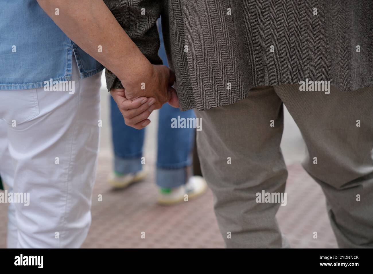 anziani anonimi che si tengono per mano in città Foto Stock