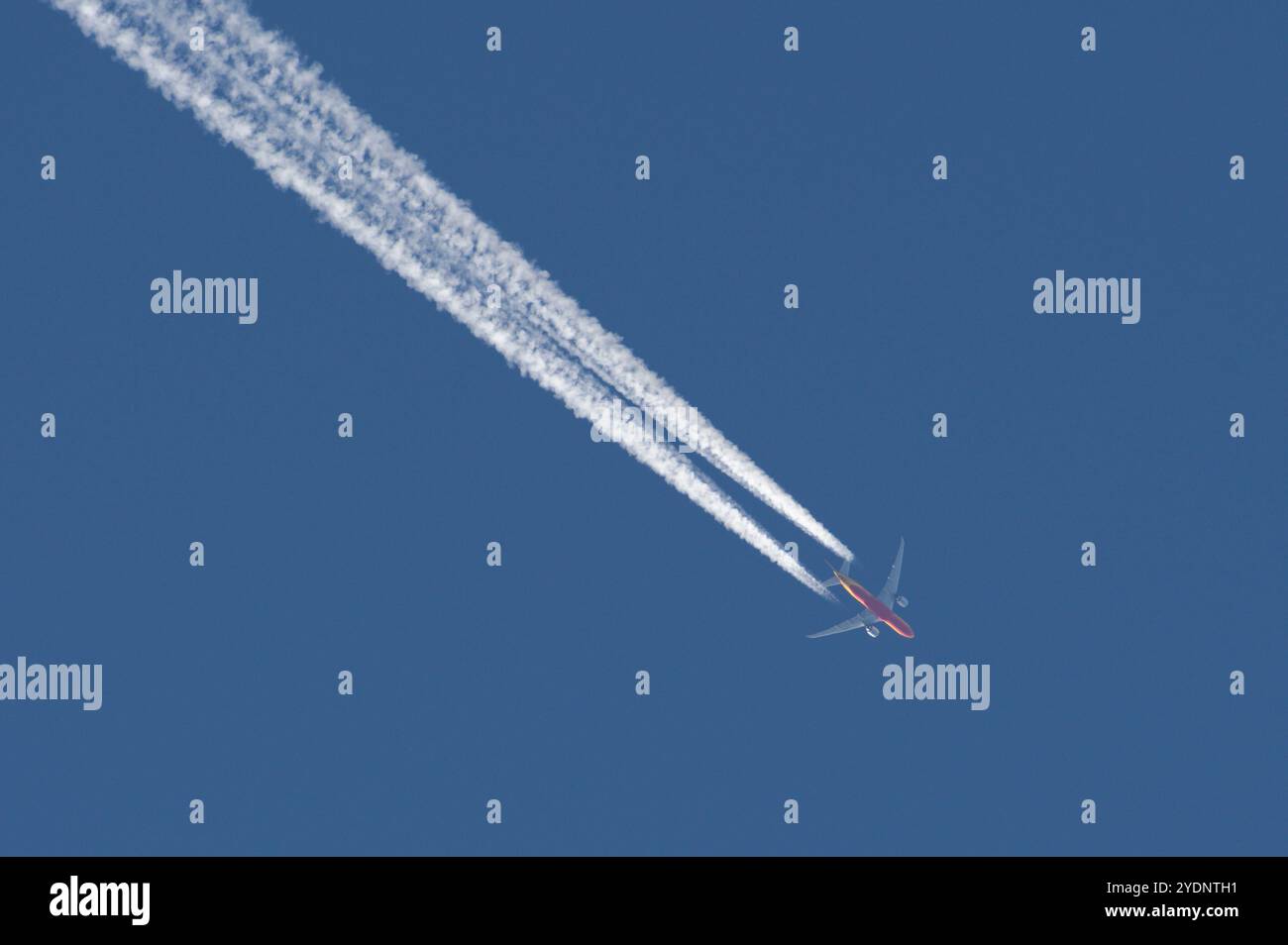 L'aereo da trasporto fa la linea molto forte di tracce chimiche sul cielo blu. Teoria della cospirazione. Foto Stock