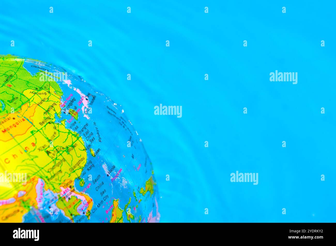 Palla da spiaggia a forma di terra che galleggia sulla superficie dell'acqua Foto Stock