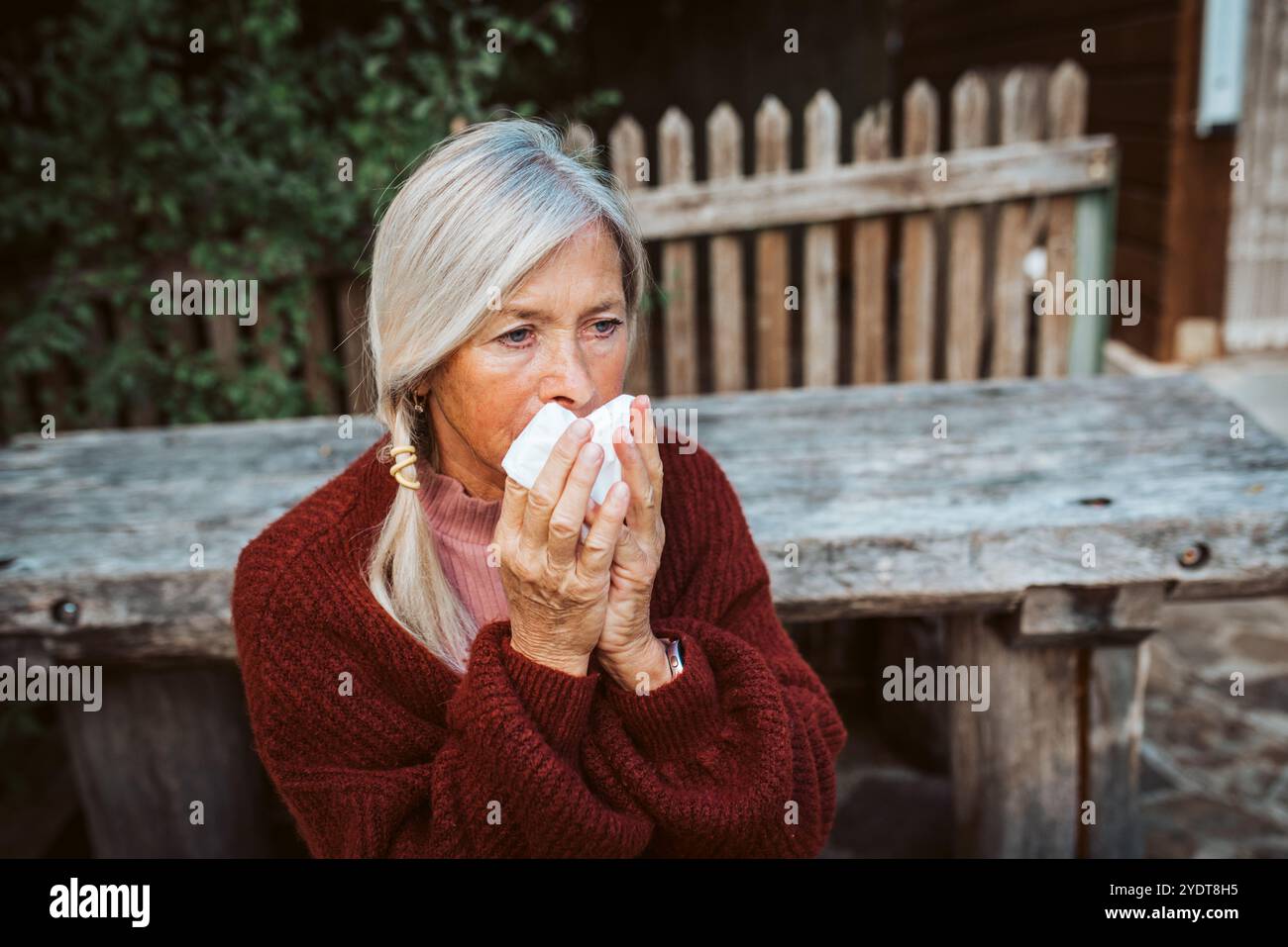 Le donne anziane si sentono male, soffiando il naso che cola e chiuso nel tessuto e starnuto. Foto Stock