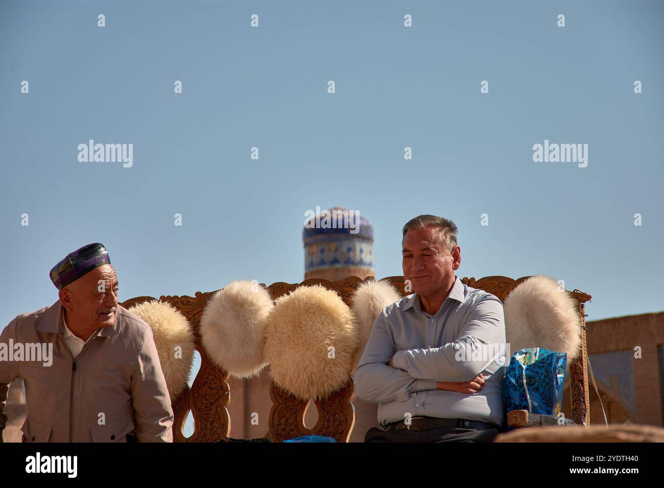 Khiva, Uzbekistan; 21 settembre 2024: Due uomini locali seduti nel vivace mercato di Khiva, Uzbekistan, che vendono tradizionali cappelli di lana realizzati in naturale Foto Stock