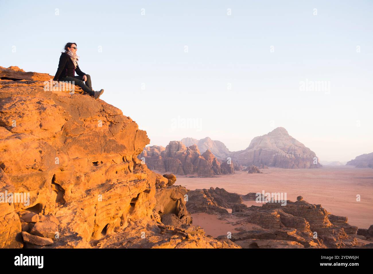 Donna che ammira il tramonto nel deserto di Wadi Rum, patrimonio dell'umanità dell'UNESCO, Giordania, Medio Oriente Foto Stock