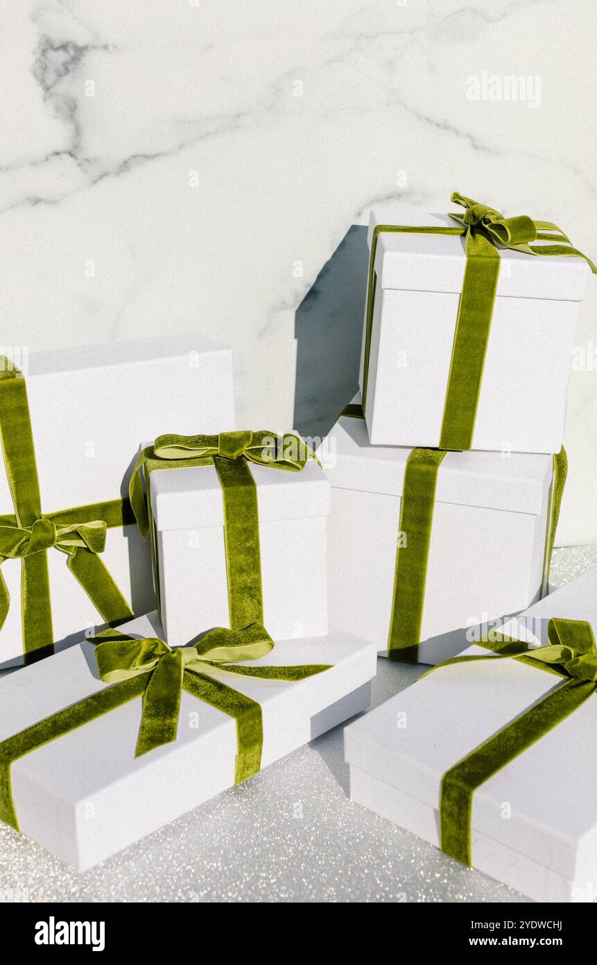 scatole regalo bianche con nastri di velluto verde su una superficie glitterata Foto Stock