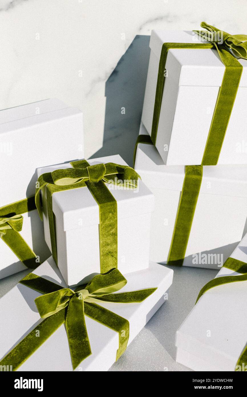 confezioni regalo impilate con nastri di velluto verde su una superficie glitterata Foto Stock