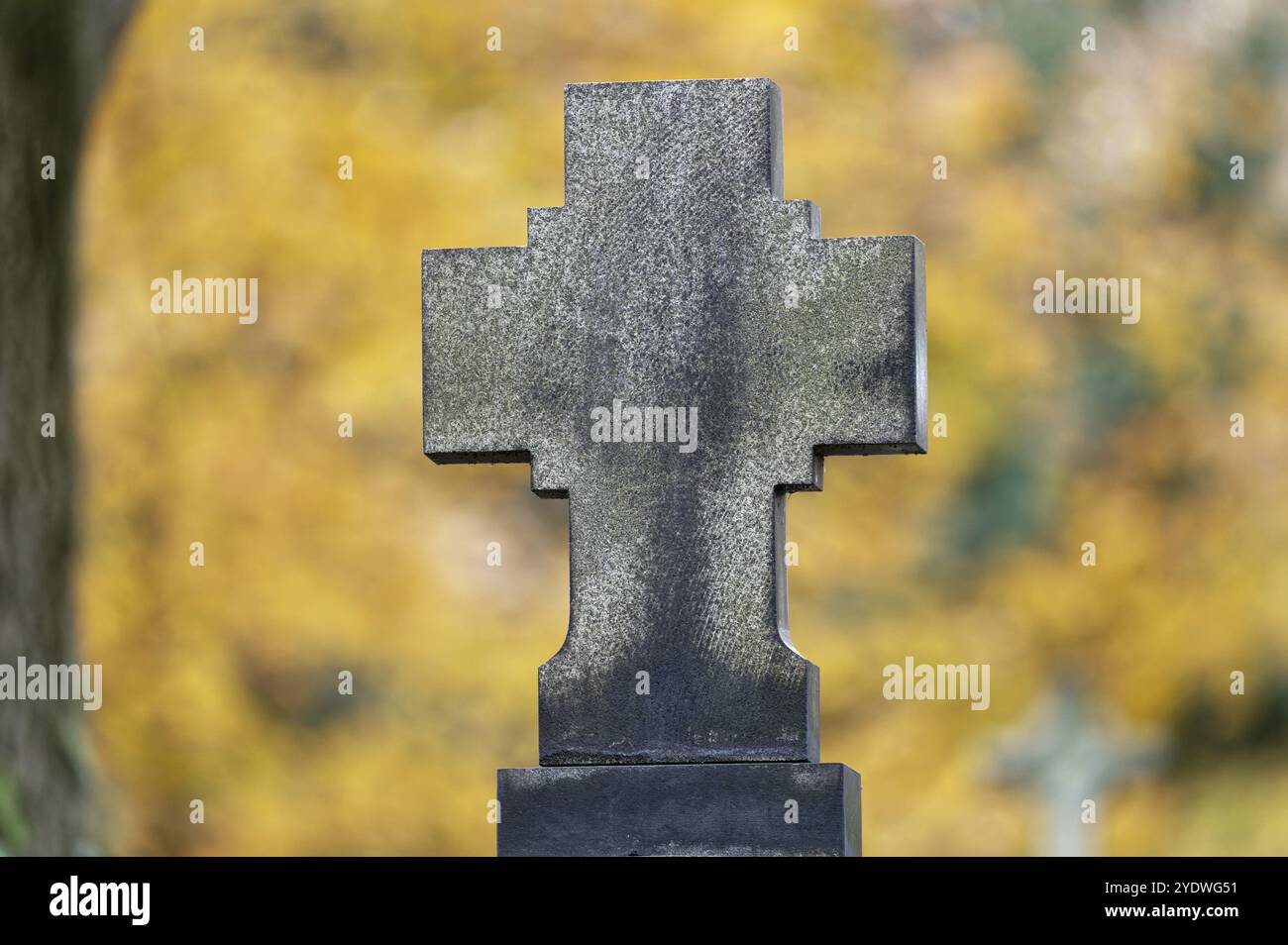 Una croce di pietra di fronte a alberi di colore autunnale su sfondo sfocato Foto Stock