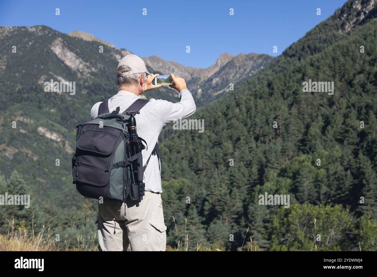 Uomo turistico caucasico medio vecchio scatta una foto dallo spagnolo Pirenei montagna con telefono cellulare Foto Stock