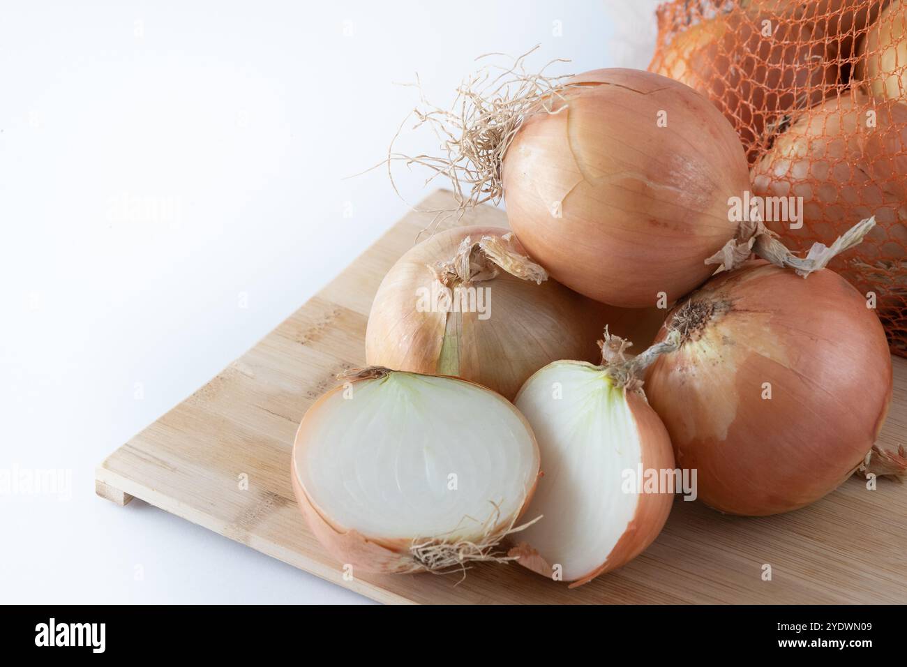 Un sacco di cipolle in un cesto e piatti su un scuro ed elegante sfondo textural.Brown cipolle e fette di legno taglio board.Healthy cibo. Foto Stock