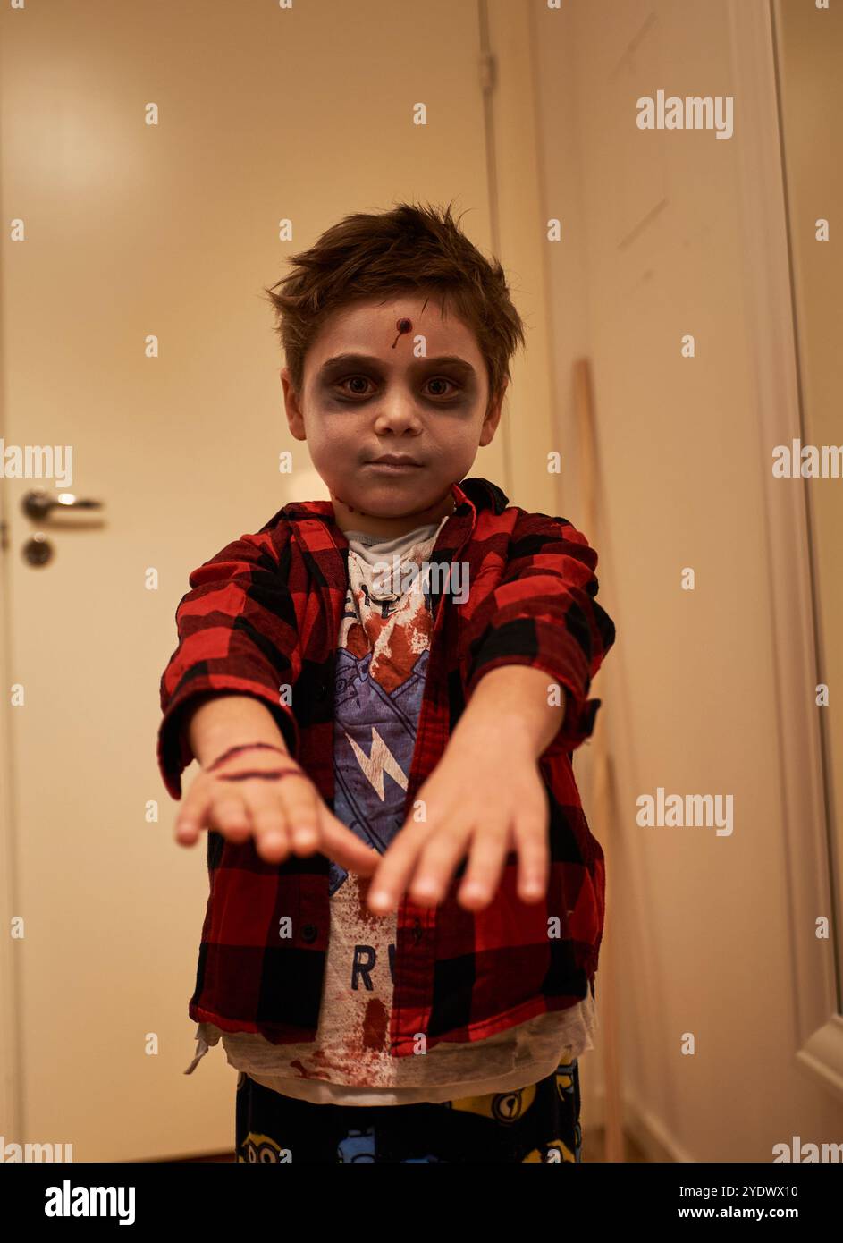 Il bambino sinistro o spaventoso finge di essere uno zombie colpito alla testa come costume di Halloween. Ragazzino spaventoso vestito come un demone di Halloween o uno spettro morto Foto Stock