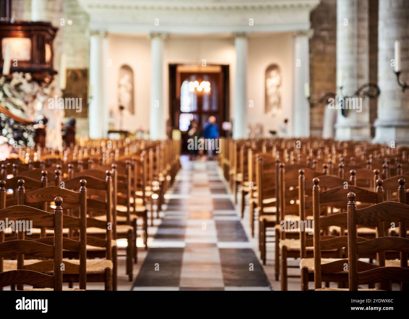 Atmosfera serena e riverente, con illuminazione soffusa che illumina lo spazio di una chiesa. Interno di una cattedrale con file di pelo o sedie in legno Foto Stock