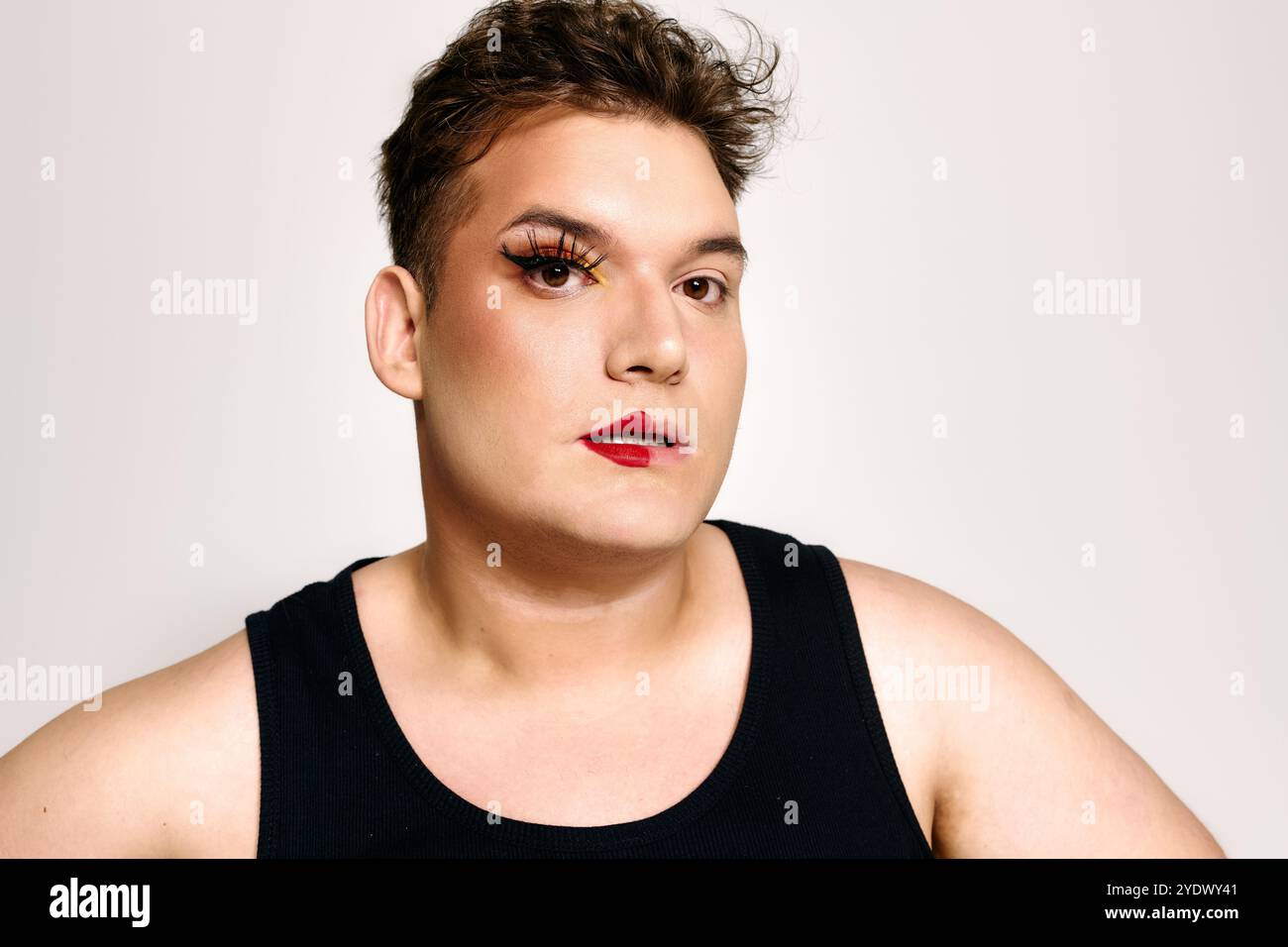 Il ritratto mette in risalto un individuo queer unico con un trucco audace, che mostra fiducia. Foto Stock