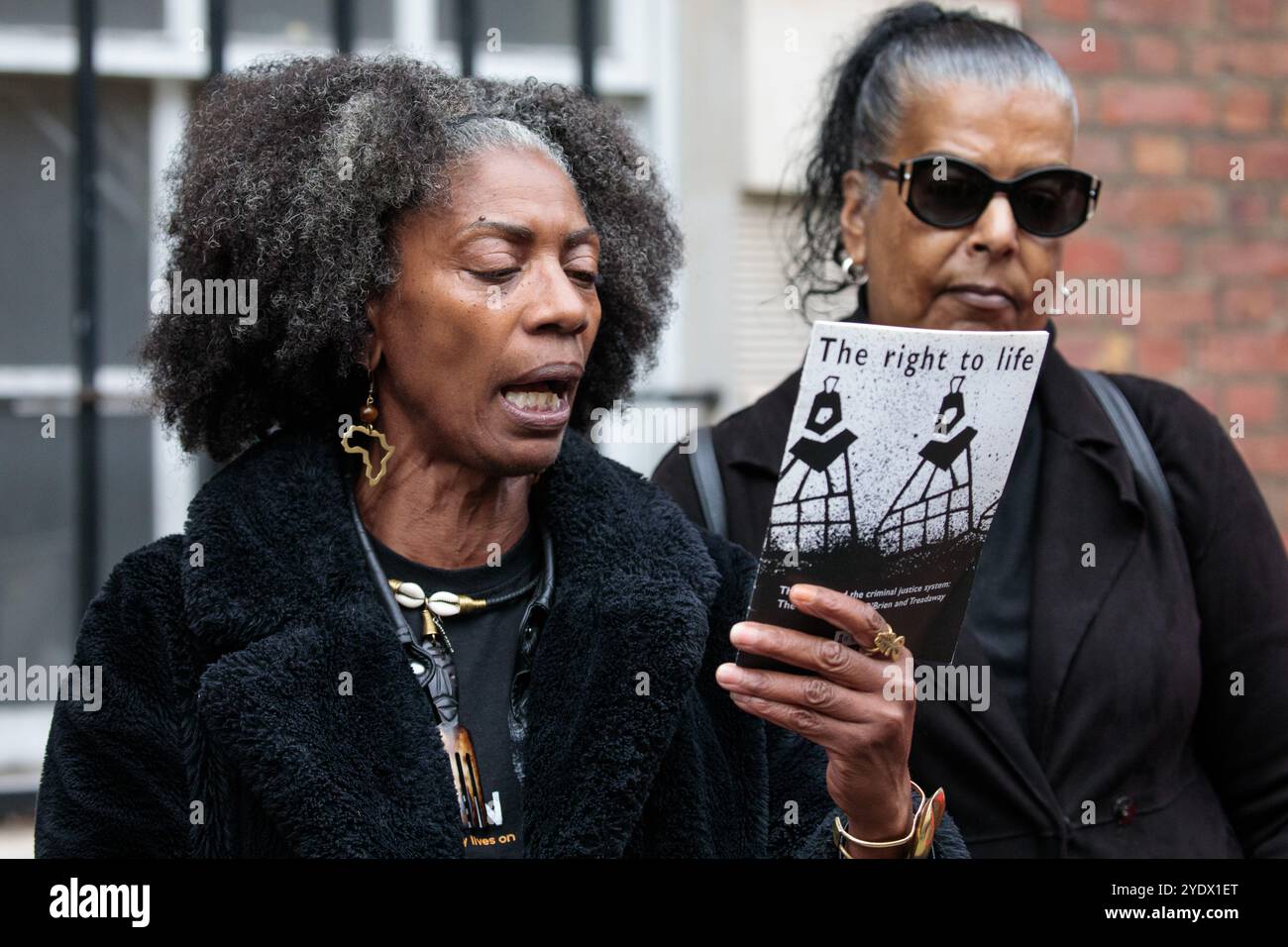 Londra, Regno Unito. 26 ottobre 2024. Marcia Rigg (l) e Susan Alexander (r) presentano una copia dell'opuscolo "il diritto alla vita" di Sir Keir Starmer (1998) prima di consegnargli una lettera in seguito alla 25a processione annuale della United Families & Friends Campaign (UFFC) in ricordo di familiari e amici morti in custodia di polizia, in carcere, in detenzione per l'immigrazione o in ospedali psichiatrici sicuri. L'UFFC è stata fondata nel 1997 come rete di sostegno alle famiglie nere, ma ora include le famiglie e gli amici di persone di varia origine etnica e culturale. Crediti: Mark Kerrison/Alamy Foto Stock