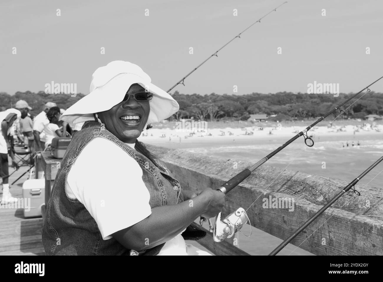 Donna afroamericana, 50-55 anni, che ride mentre pesca da un molo al Myrtle Beach State Park, South Carolina, Stati Uniti. Foto Stock