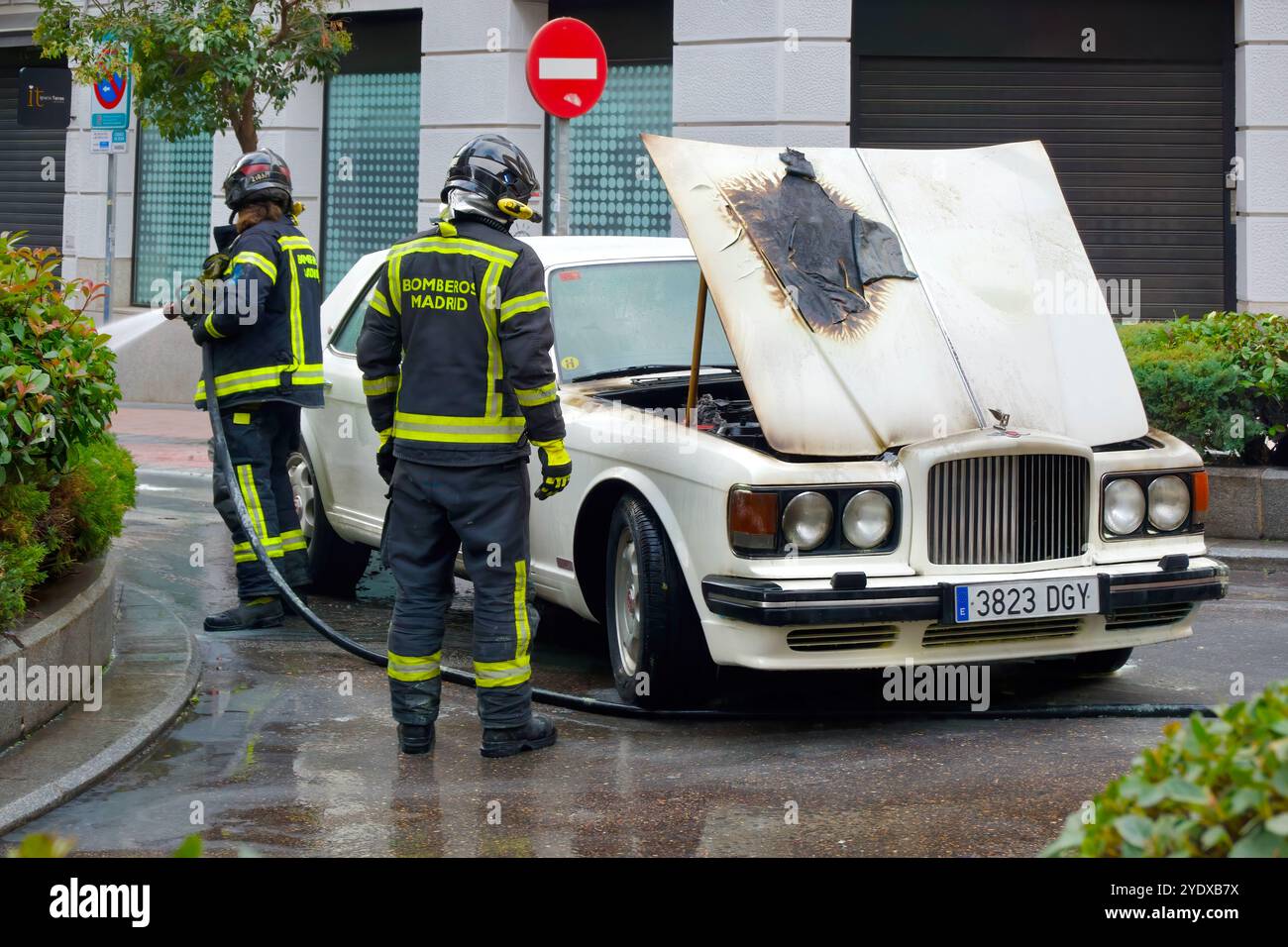 Bentley White del 1980 ha bruciato il vano motore con il cofano aperto e la polizia locale e i vigili del fuoco che assistono in una strada del centro città Madrid Spagna Foto Stock