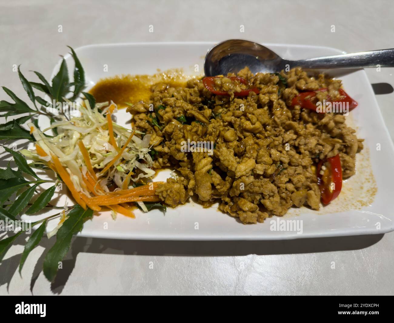 Mescolare il maiale macinato tailandese con foglie di basilico e peperoncini rossi. Preparazione di maiale in stile thailandese o piatti asiatici. Foto Stock