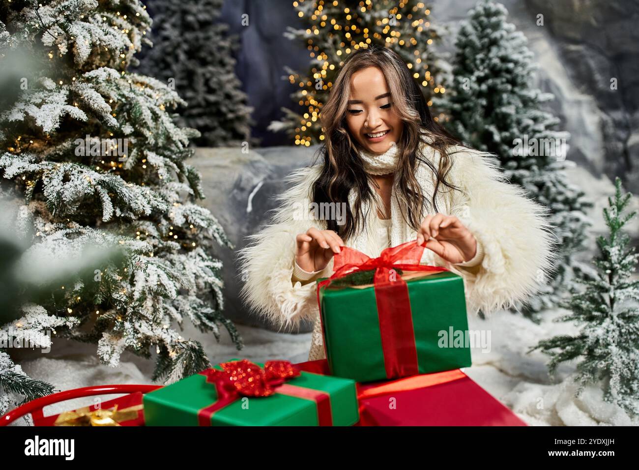 Una persona allegra sfoggia un regalo verde con un nastro rosso in una scena di festa innevata. Foto Stock