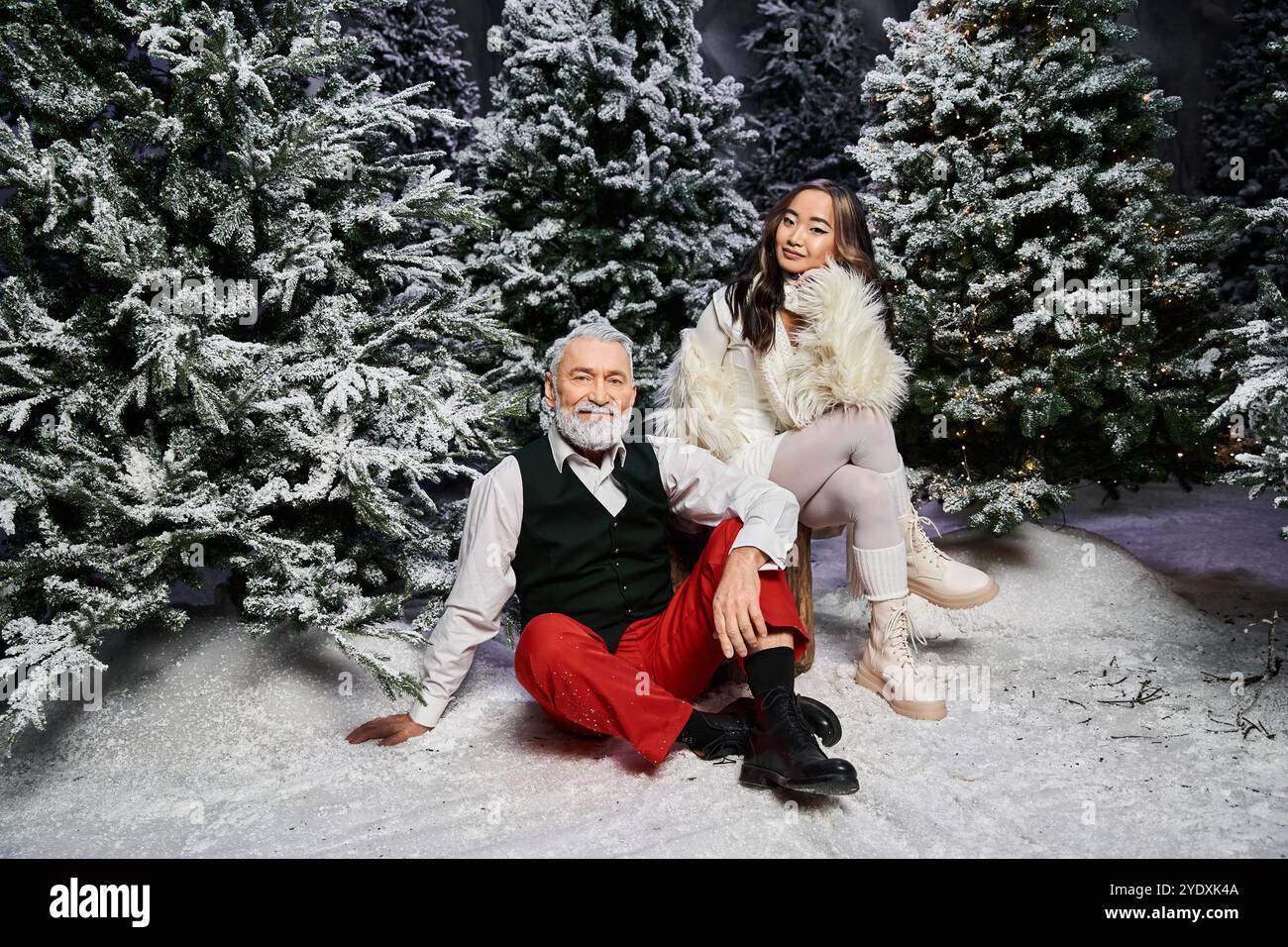 Un uomo e una donna godono di un'atmosfera natalizia, circondati da alberi innevati. Foto Stock