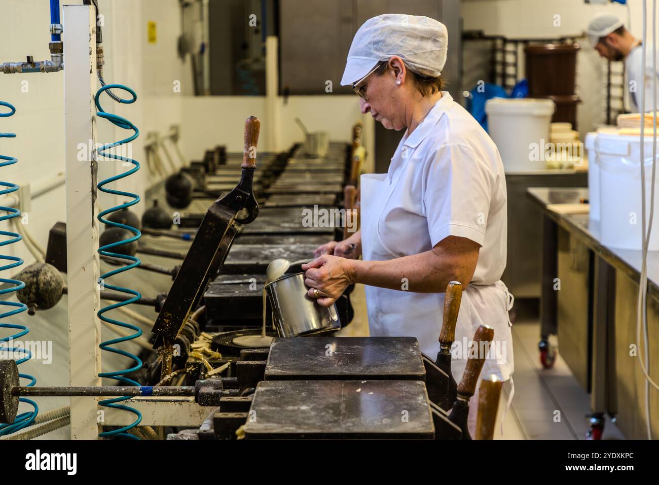 Un dipendente versa la pastella nel pesante ferro per waffle della fabbrica La Serenissima; dopo quattro minuti il waffle è cotto. La Torta Tre Monti è composta da diversi strati di wafer e cioccolato fondente. Via XXV Marzo, Domagnano, San Marino. Foto Stock