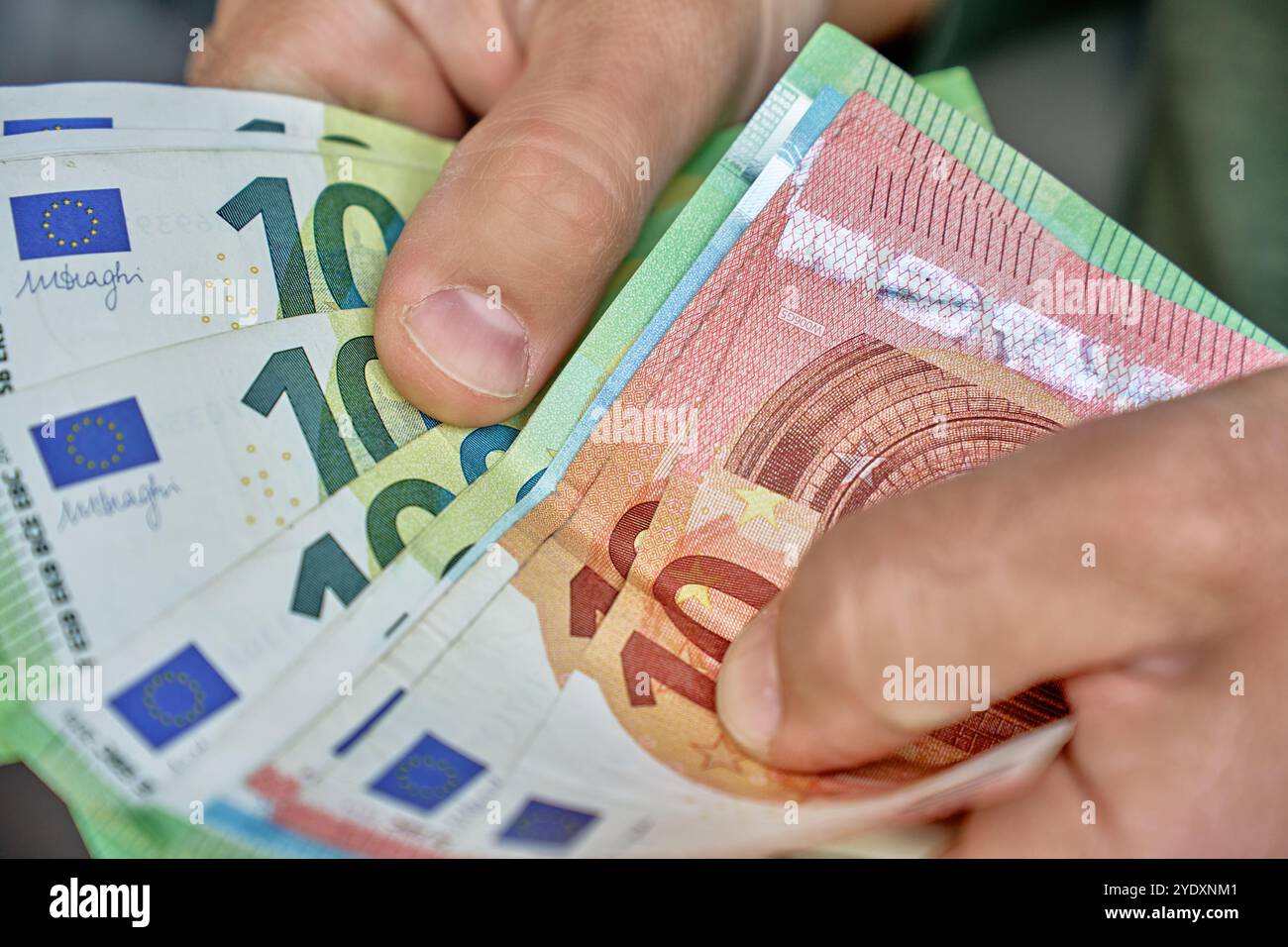 Primo piano del conteggio manuale delle banconote in euro. Uomo che tiene in mano soldi di carta in contanti. Concetto di gestione del contante, ricchezza o transazioni finanziarie Foto Stock