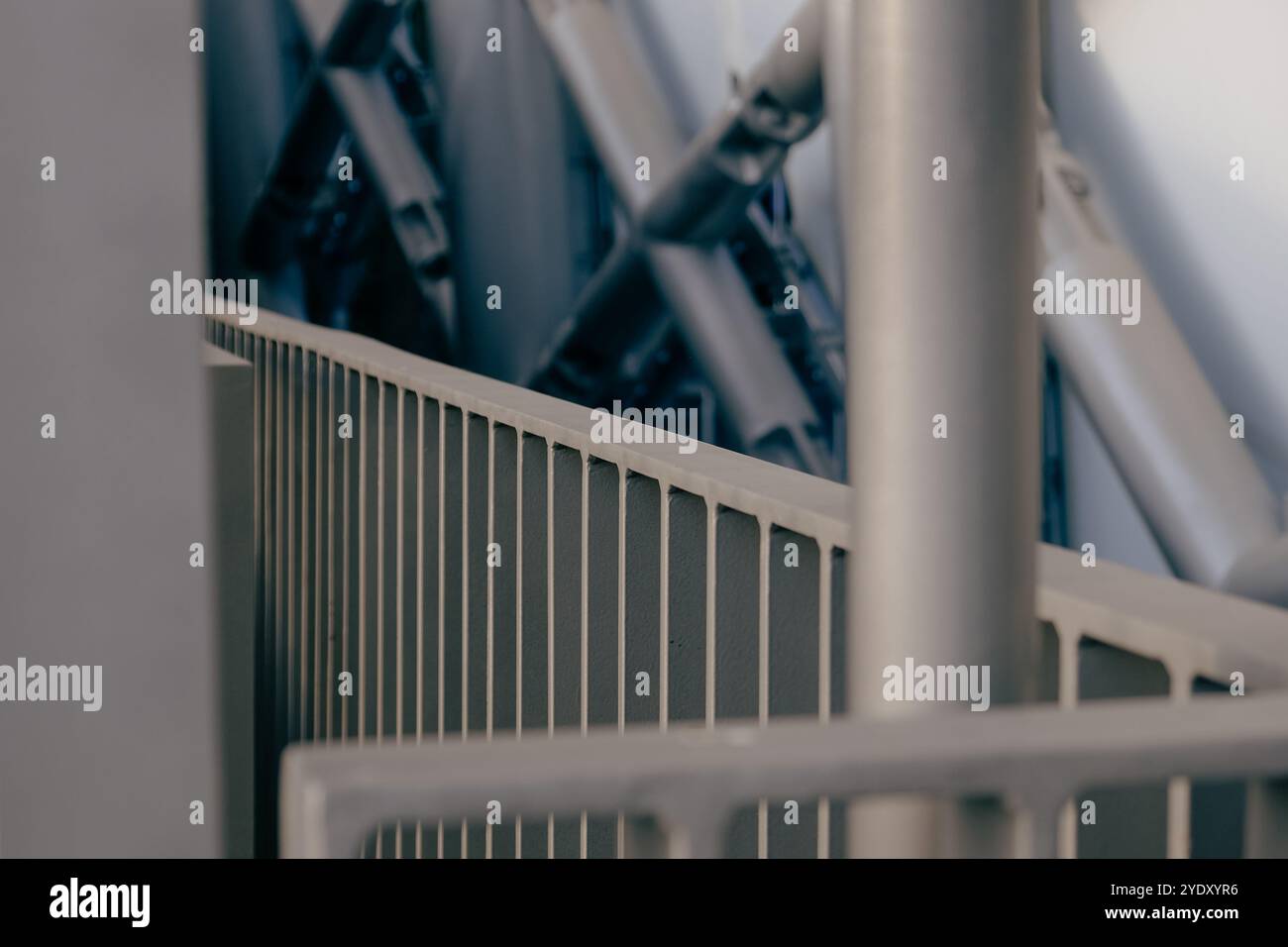 Una prospettiva ravvicinata di un design architettonico mette in mostra travi metalliche intersecanti e un'elegante ringhiera, mettendo in risalto le moderne tecniche di costruzione Foto Stock