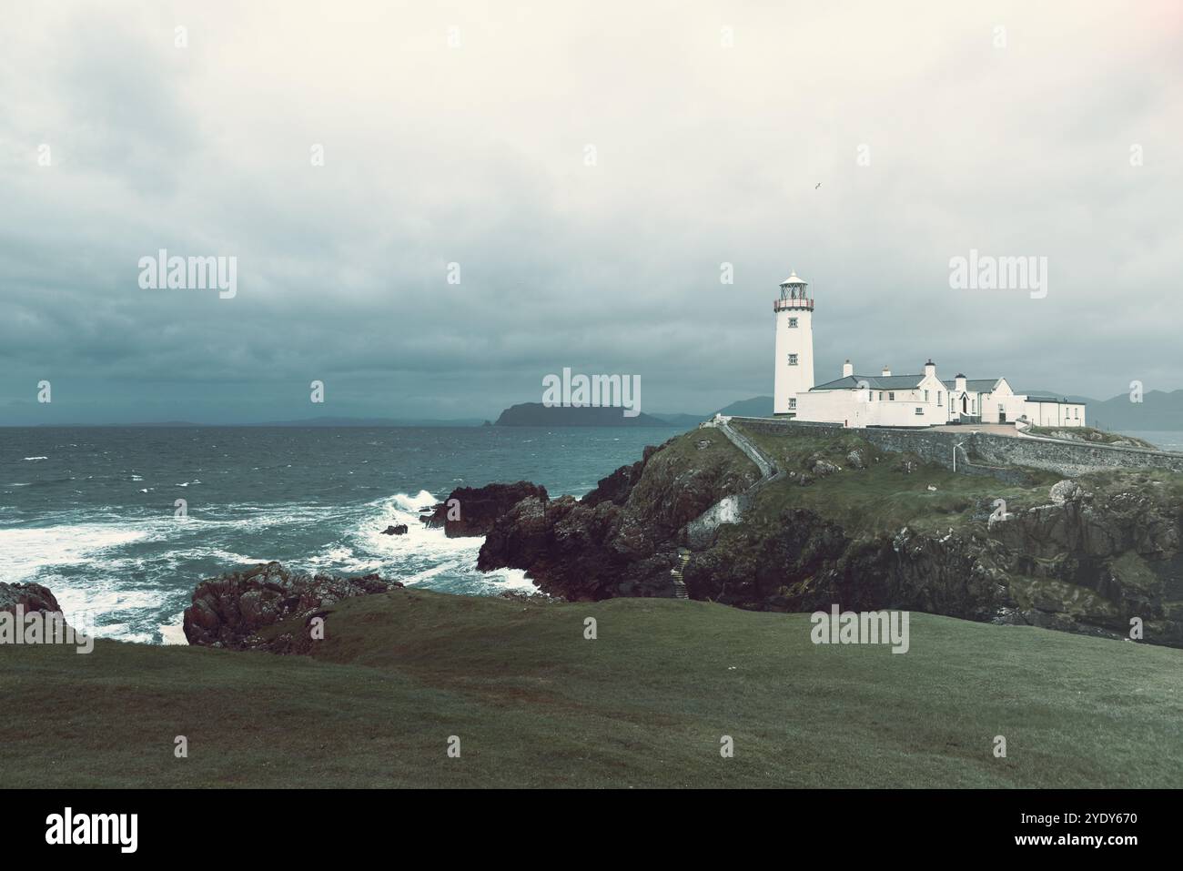 Fanad Head Lighthouse è resistente all'Atlantico tempestoso, con tonalità vintage che aggiungono una qualità senza tempo. Le onde drammatiche e il cielo coperto Foto Stock