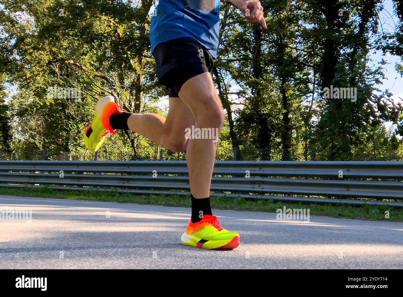 gambe da vicino corridore maschile con scarpe da running brillanti corre su strada Foto Stock