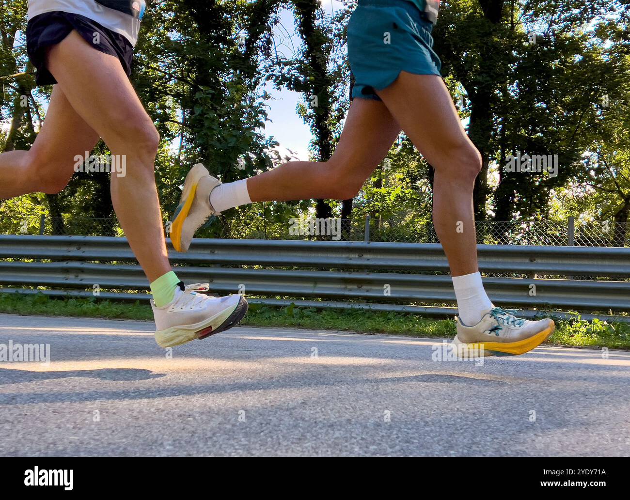 le gambe due atleti corrono su strada asfaltata nel parco Foto Stock