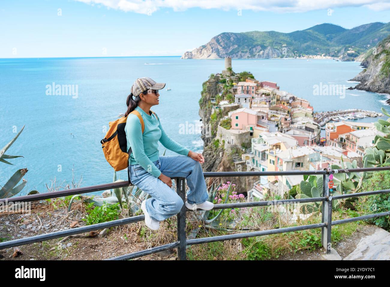 Un viaggiatore fa una pausa su una ringhiera, ammirando la splendida vista costiera delle cinque Terre. Vernazza Italia Foto Stock