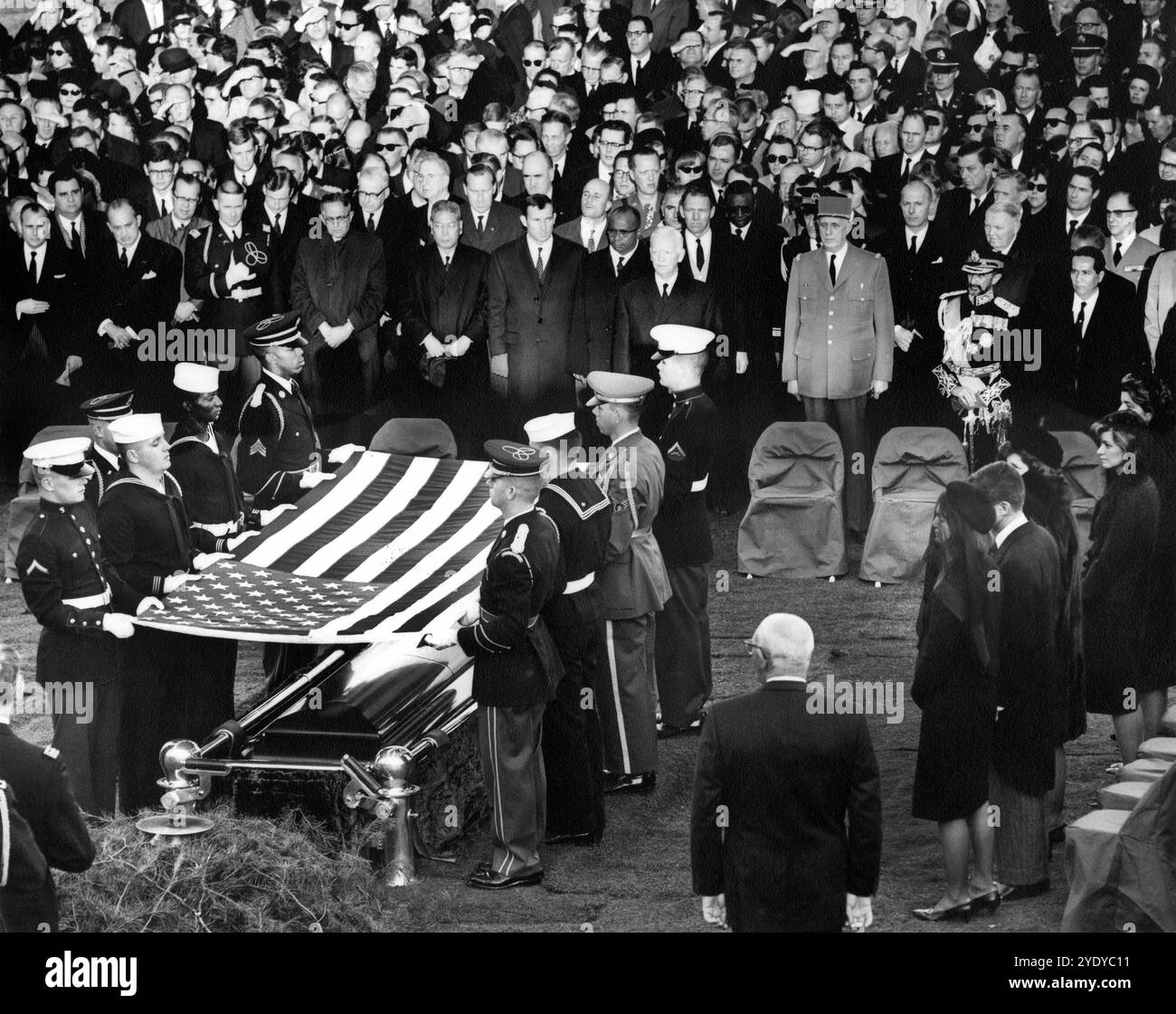 I membri della famiglia Kennedy, i funzionari e i dignitari si guardano come guardiani d'onore sollevano la bandiera del presidente degli Stati Uniti John F. Kennedy al cimitero, durante i funerali di stato del presidente Kennedy, Arlington National Cemetery, Arlington, Virginia, USA, Abbie Rowe, White House Photographs, 25 novembre 1963 Foto Stock
