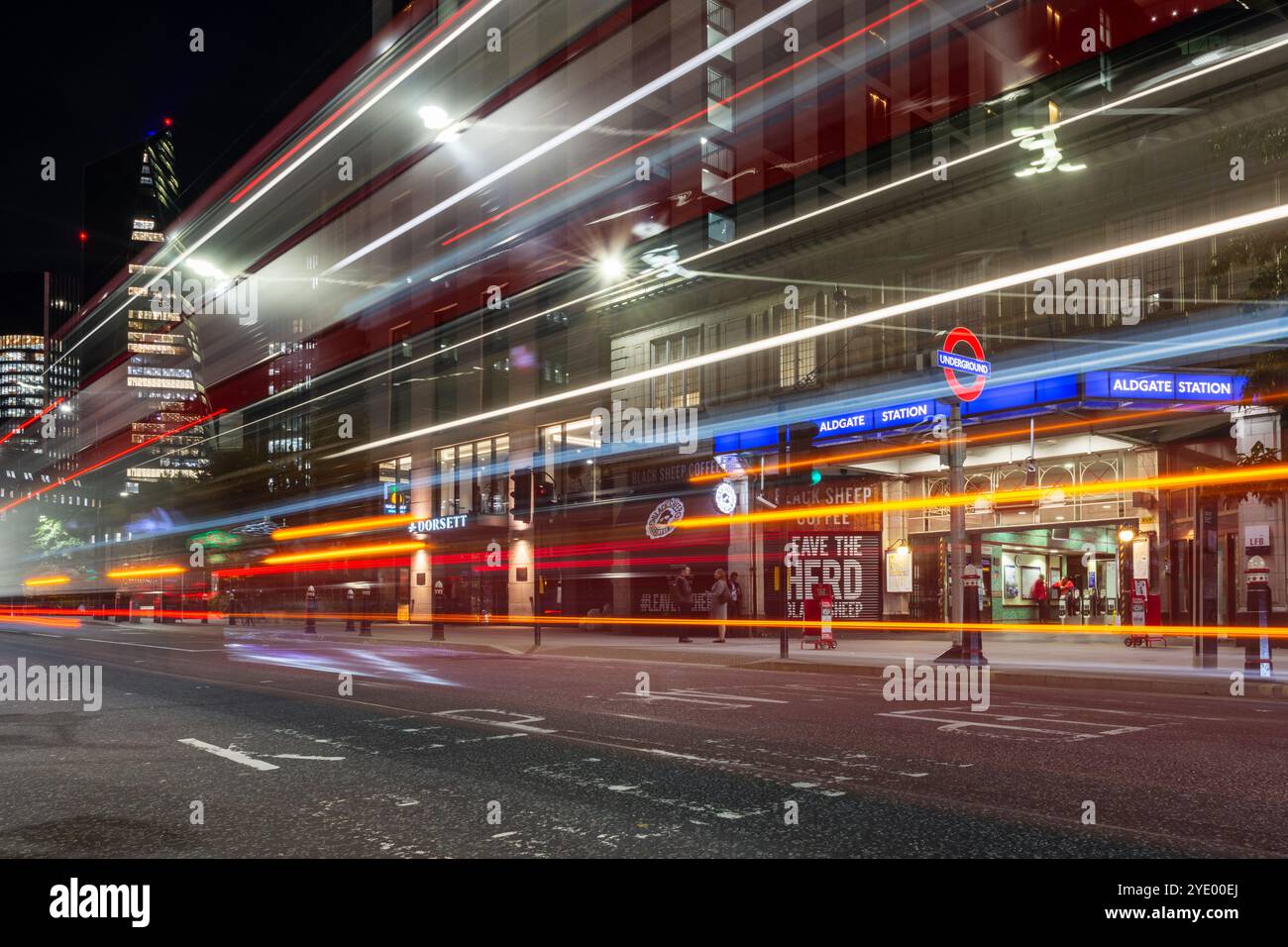 Il traffico lascia sentieri leggeri di notte fuori dalla stazione di Aldgate nella City di Londra. Foto Stock