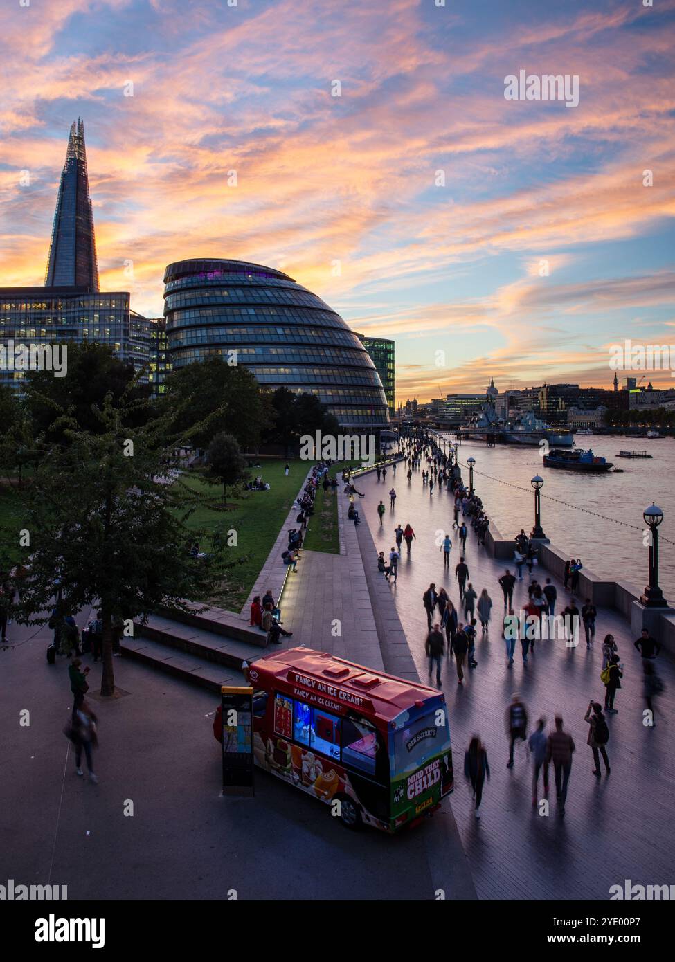 I turisti camminano lungo la sponda sud del Tamigi a Southwark, Londra, al tramonto. Foto Stock
