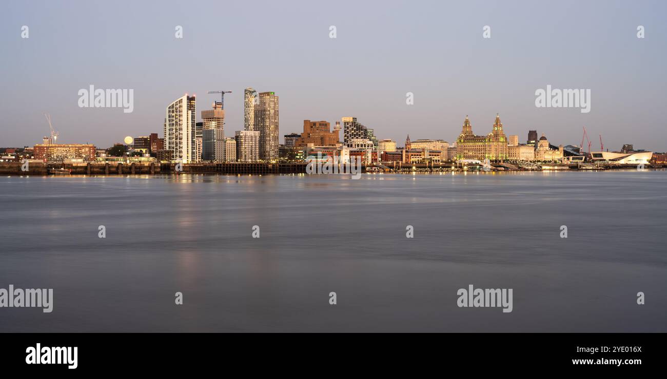 La luna sorge dietro gli edifici di appartamenti a torre dello sviluppo di Liverpool Waters docklands, visto dall'altra parte del Mersey. Foto Stock