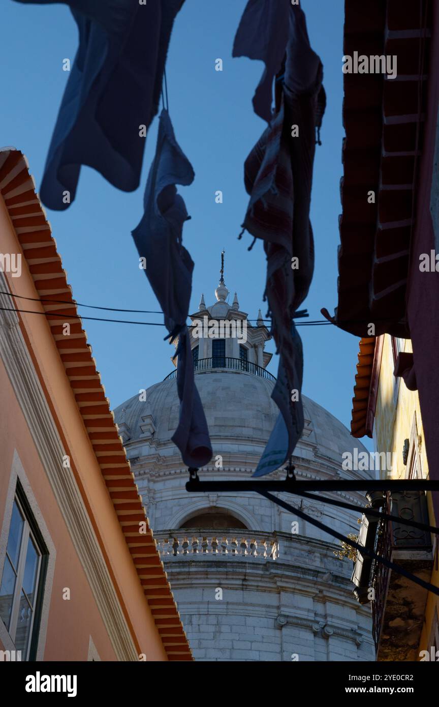 La cupola Panteão Nacional sbircia attraverso la lavanderia sospesa nell'Alfama di Lisbona, mescolando architettura monumentale con la vita quotidiana Foto Stock