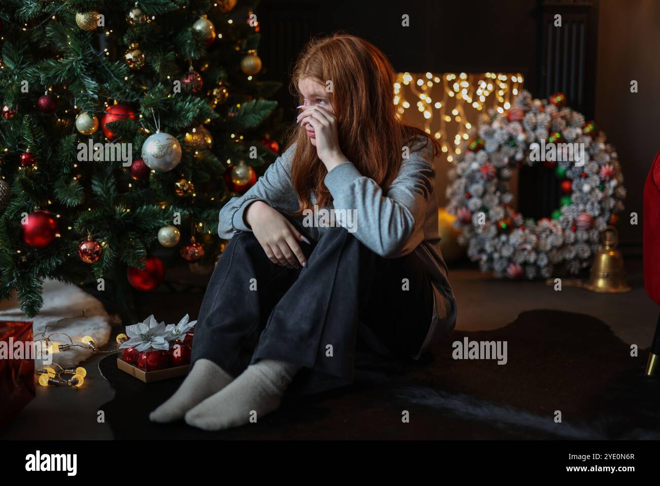 Giovane bella depressa e triste ragazza seduta da sola per la vigilia di Natale Foto Stock