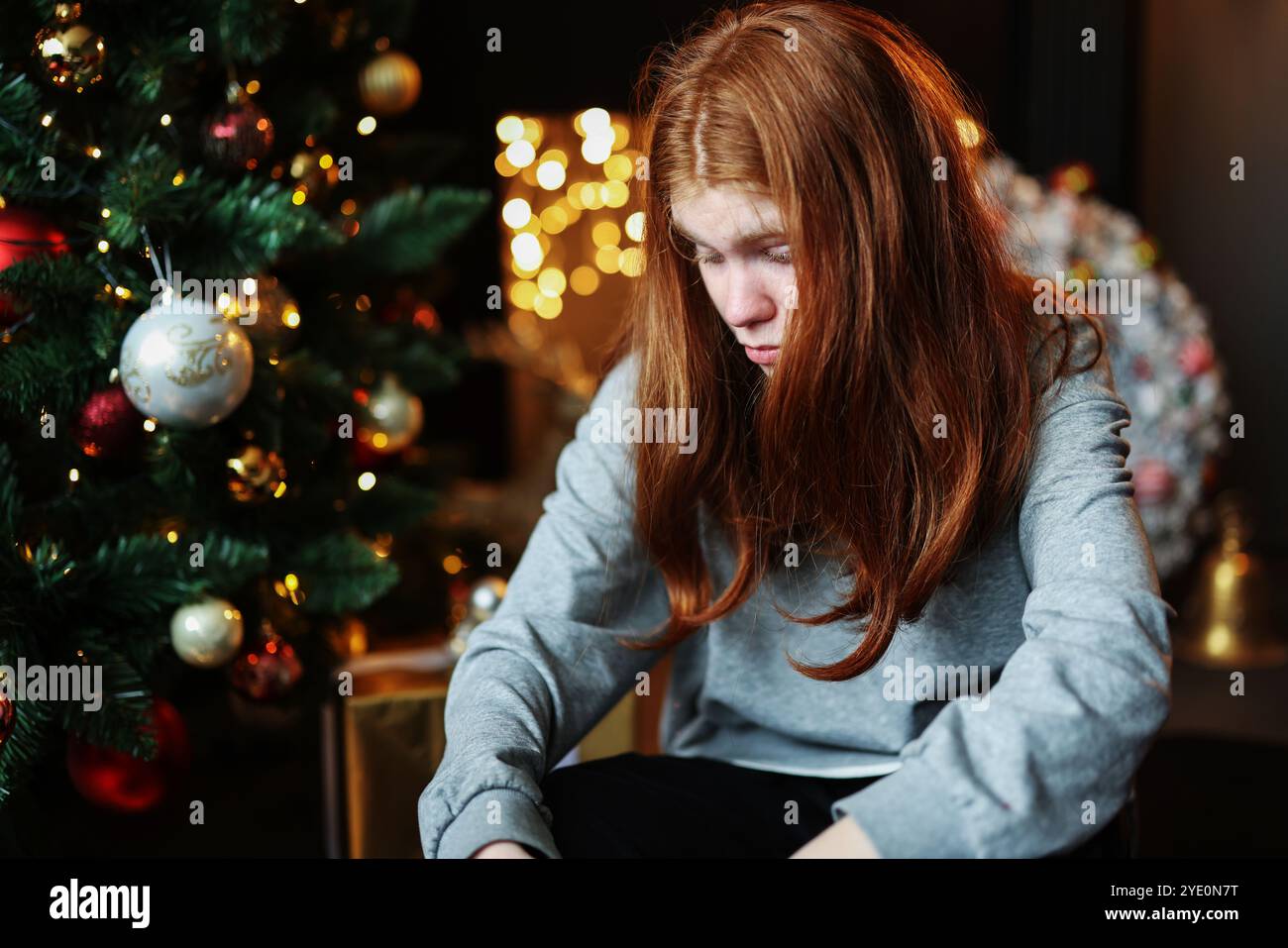 Giovane bella depressa e triste ragazza seduta da sola per la vigilia di Natale Foto Stock