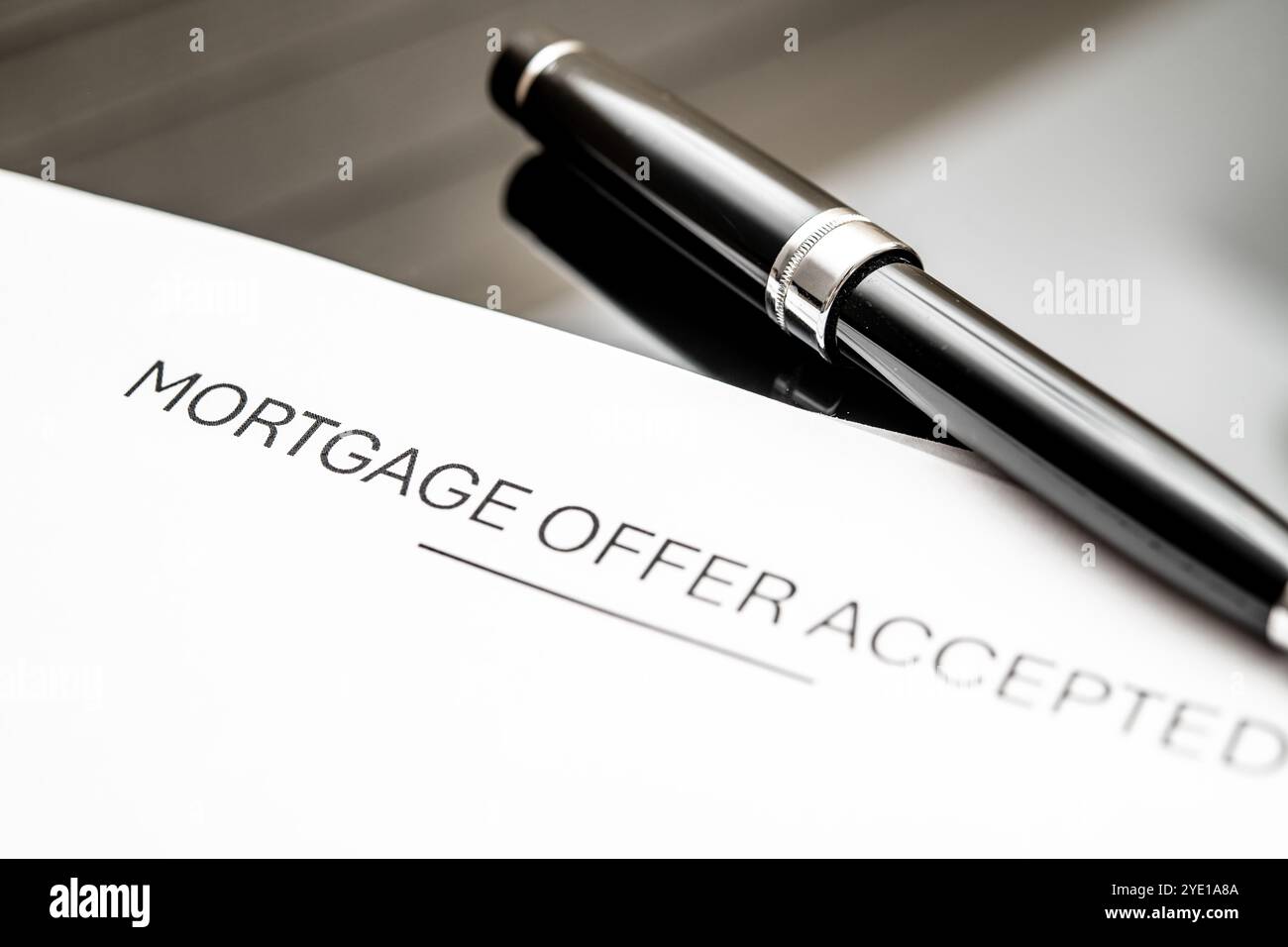 Un documento di offerta ipotecaria accettato accanto a una penna elegante su una scrivania moderna, che simboleggia le transazioni immobiliari, le approvazioni finanziarie, l'acquisto di abitazioni, e. Foto Stock