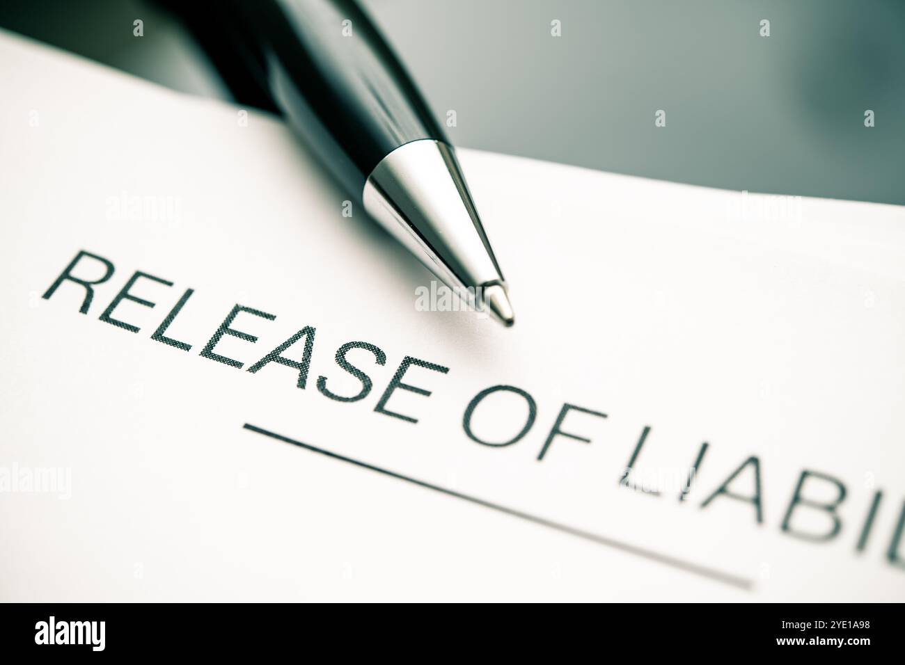 Vista ravvicinata di un documento sulla liberazione di responsabilità con una penna, che sottolinea accordi legali, deroghe, gestione dei rischi e termini cruciali per la protezione Foto Stock