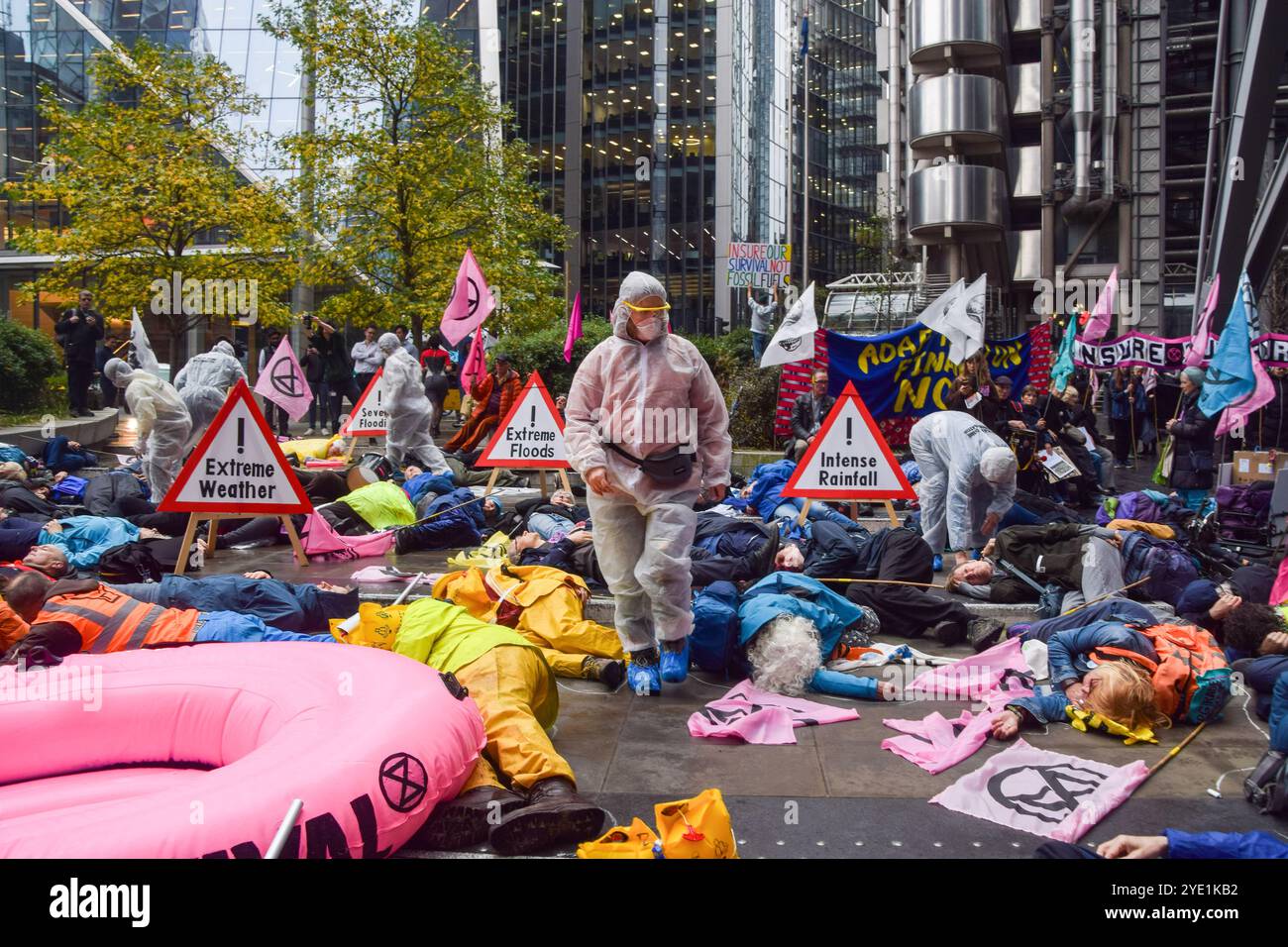 Londra, Regno Unito. 28 ottobre 2024. Gli attivisti della ribellione di Extinction, alcuni indossano abiti da hazmat, mettono in scena un "die-in" fuori dalla sede dei Lloyd's di Londra mentre iniziano tre giorni di proteste nella City di Londra, il quartiere finanziario della capitale, chiedendo alle compagnie assicurative di smettere di assicurare progetti di combustibili fossili. (Foto di Vuk Valcic/SOPA Images/Sipa USA) credito: SIPA USA/Alamy Live News Foto Stock