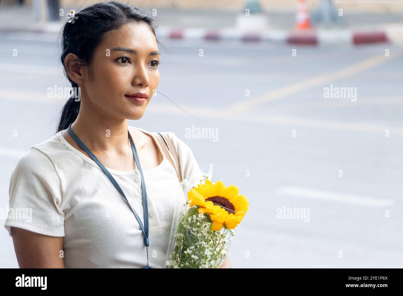 Una giovane donna sta con un fiore per strada Foto Stock