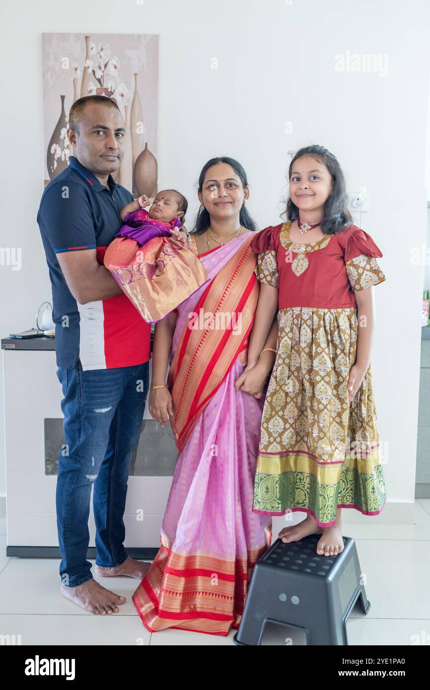 Una famiglia indiana che indossa costumi tradizionali e informali trascorre del tempo con il loro bambino, la ragazza e i nonni in un alto edificio di appartamenti a Kuala Foto Stock