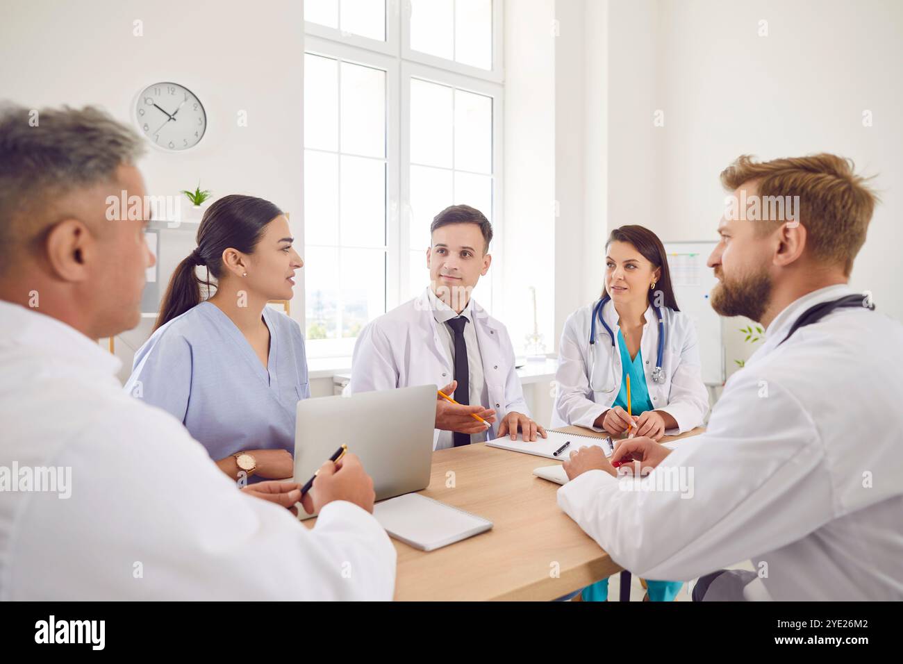 Incontro medico sicuro, chirurghi, personale infermieristico in uniforme bianca che parla con i colleghi alla scrivania Foto Stock