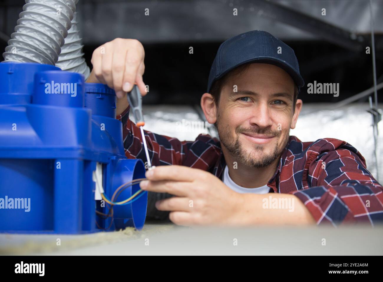 un tecnico di ventilazione sorridente con un cacciavite Foto Stock