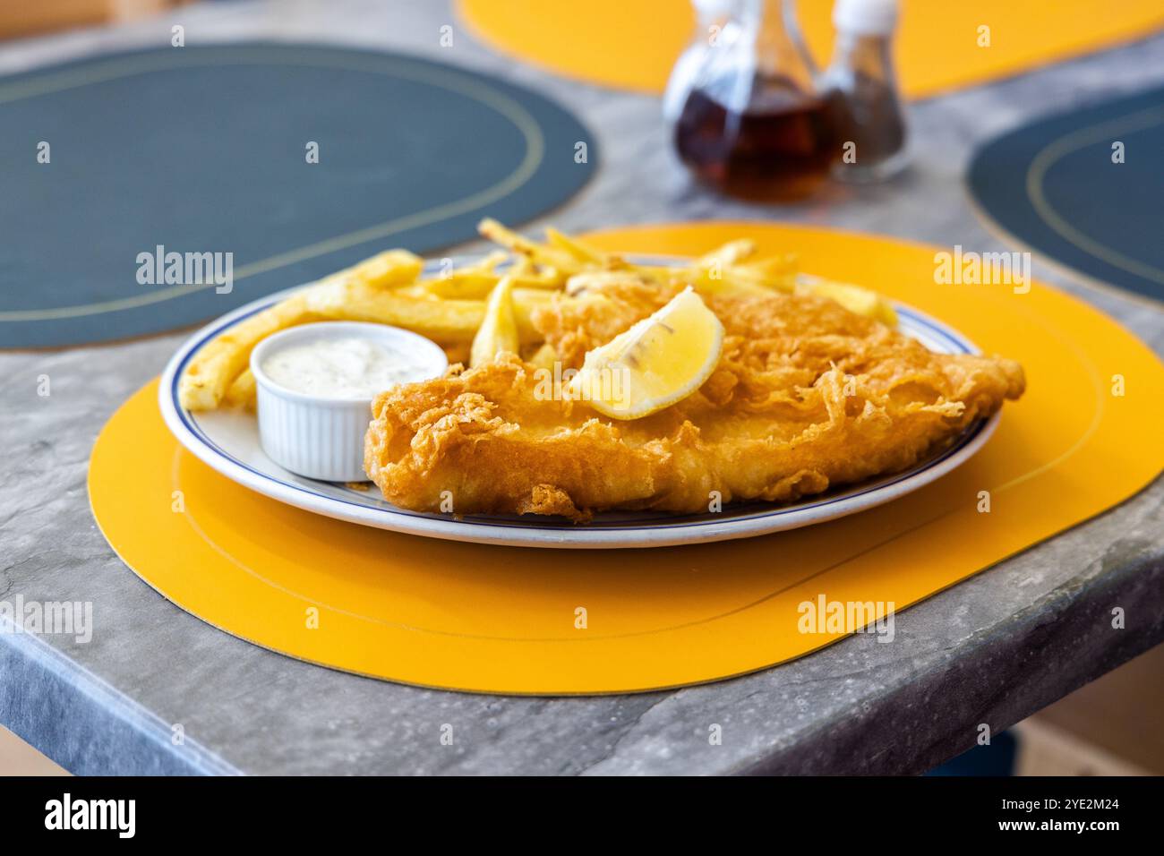 pesce e patatine su un piatto con condimenti Foto Stock