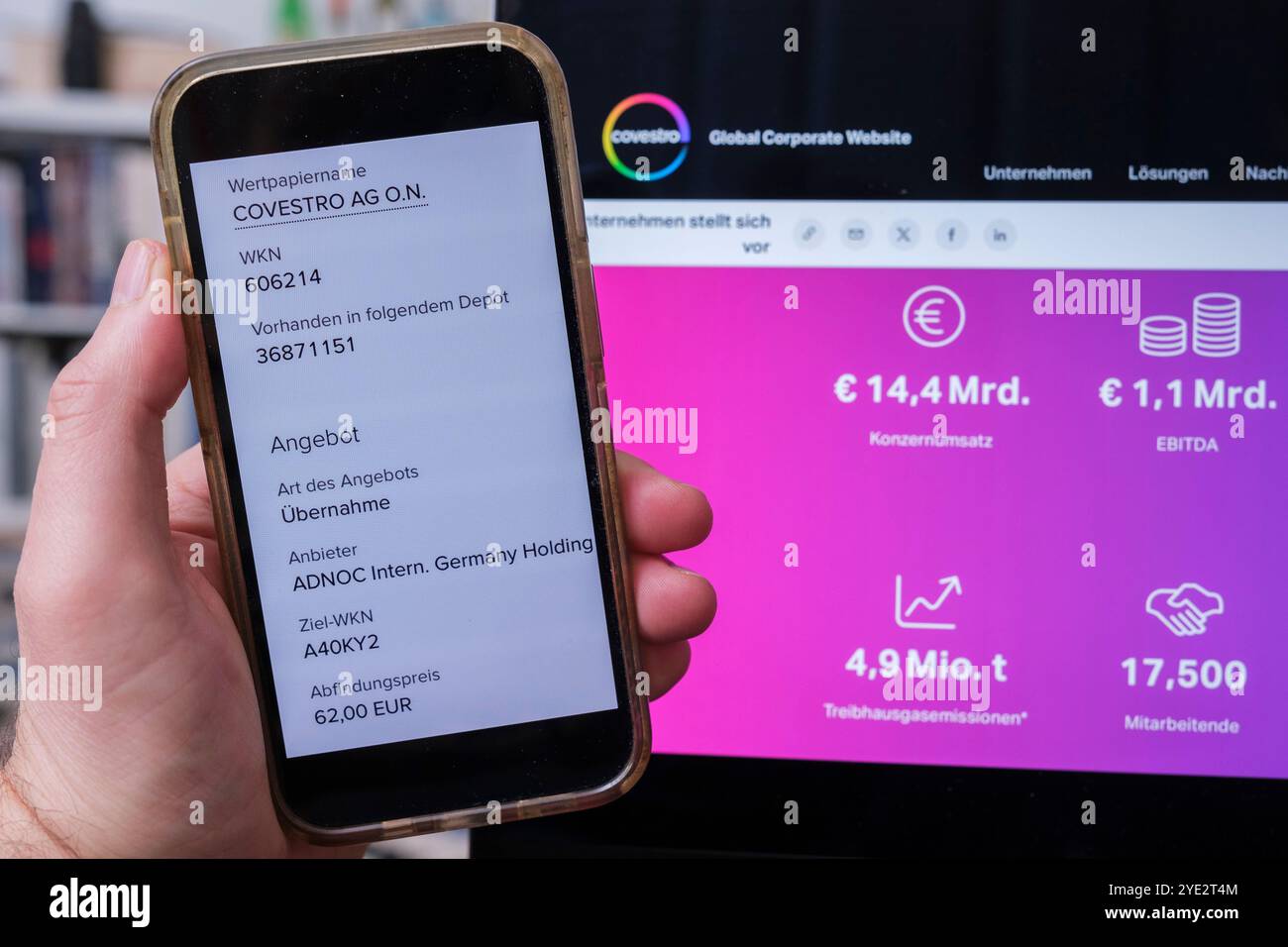 Covestro: Tenere a mano il cellulare che mostra l'offerta di acquisto di ADNOC Foto Stock
