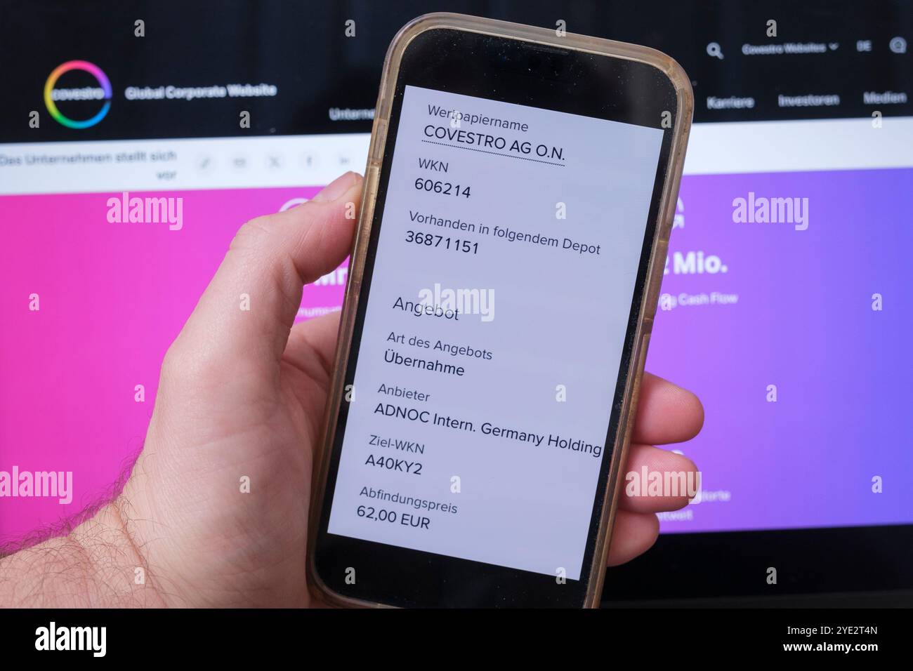Covestro: Tenere a mano il cellulare che mostra l'offerta di acquisto di ADNOC Foto Stock