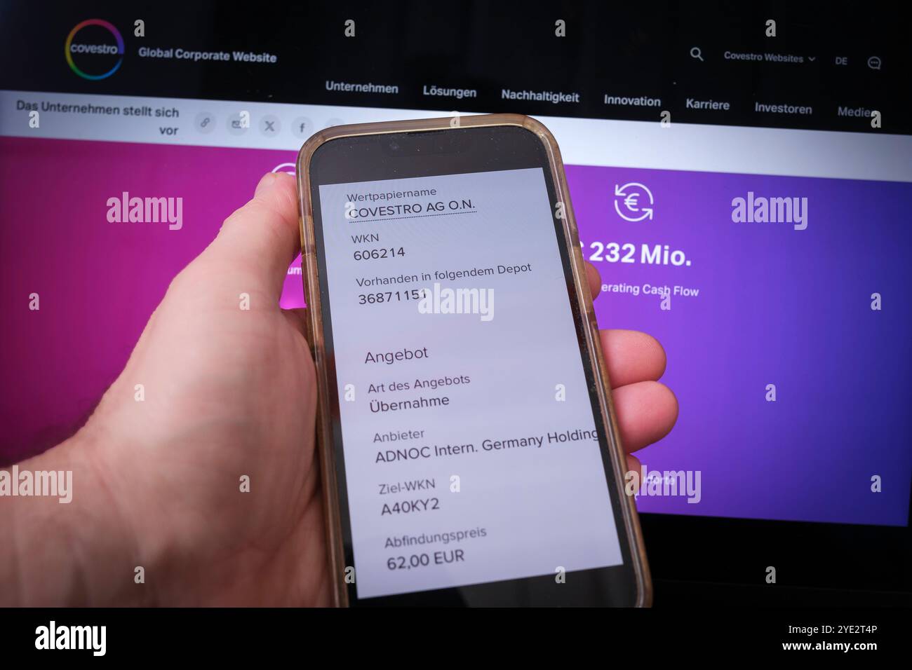 Covestro: Tenere a mano il cellulare che mostra l'offerta di acquisto di ADNOC Foto Stock