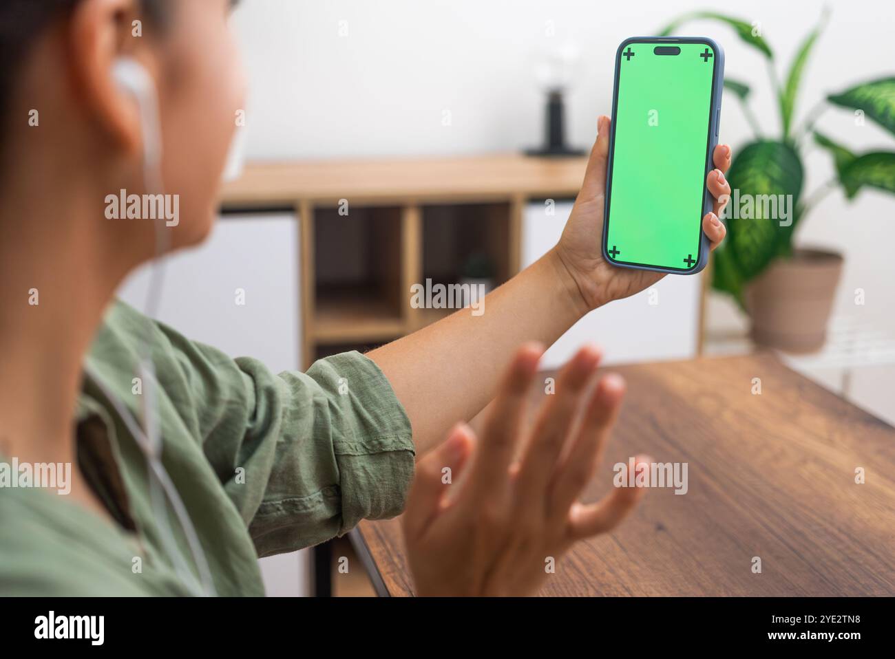 Una donna in cuffia trasmette un saluto che comunica con un amico durante una videochiamata sul telefono cellulare Foto Stock
