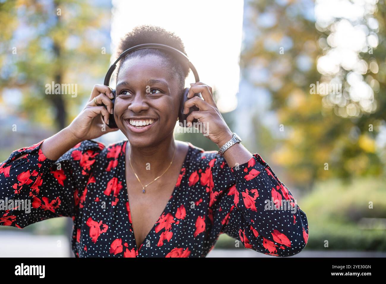 Giovane donna che ascolta musica con le cuffie in città Foto Stock