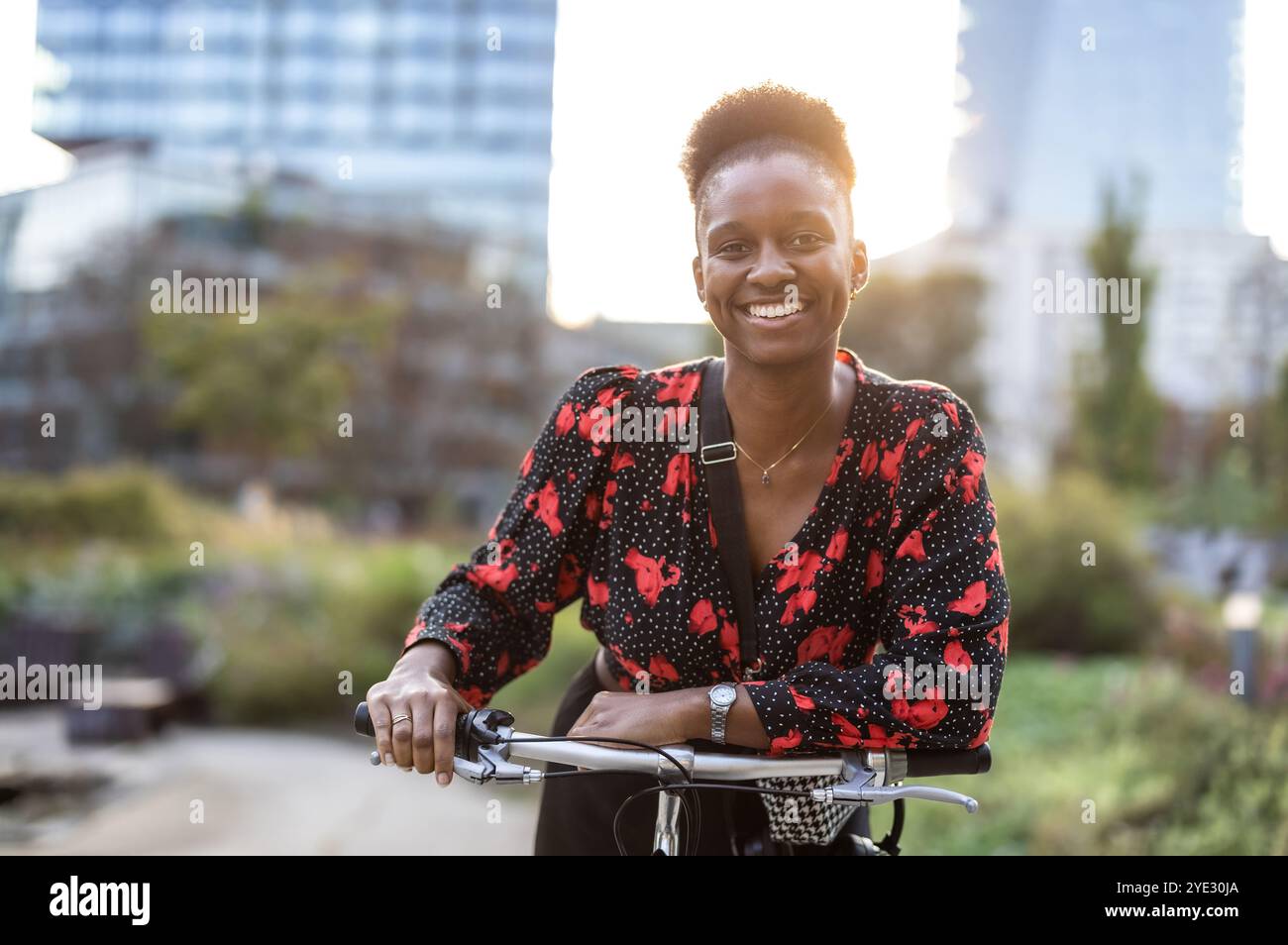 Ritratto di una giovane donna sorridente con la sua bicicletta in città Foto Stock