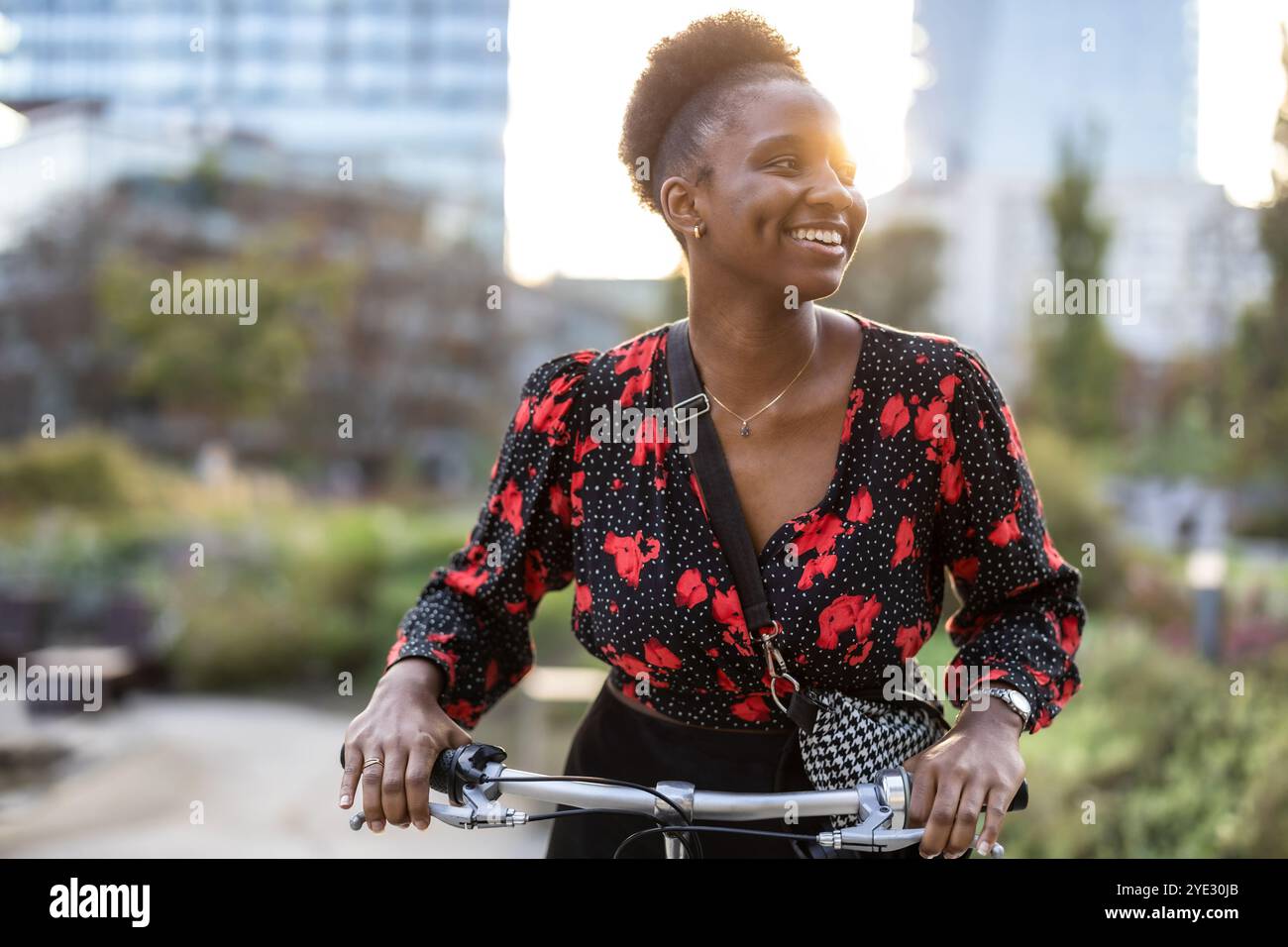 Ritratto di una giovane donna sorridente con la sua bicicletta in città Foto Stock